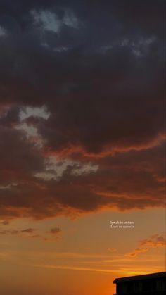 an airplane flying in the sky at sunset with clouds and sun going down behind it