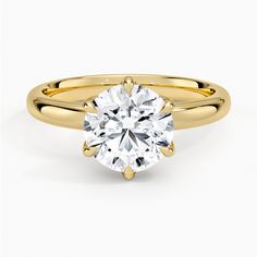 a yellow gold engagement ring with a round cut diamond in the center, on a white background