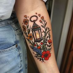 a woman's arm with a lantern and flowers on it