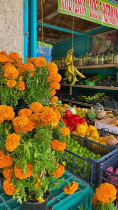 an outdoor market with orange flowers and other fruits and vegetables for sale on the shelves