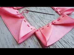 a pink piece of fabric being sewn together with scissors and thread on the table