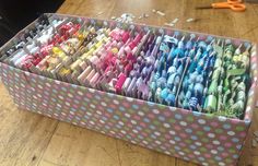 a box filled with lots of different colored toothbrushes on top of a wooden table