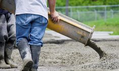 two men are walking in the mud with a large bucket and shovel on their feet