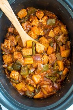 a wooden spoon in a slow cooker filled with food