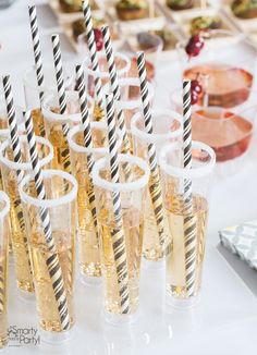 there are many glasses that have black and white striped straws in them on the table