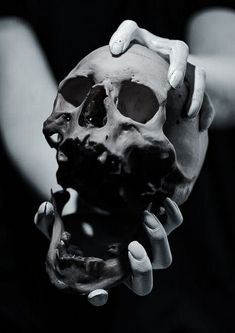 a human skull being held by two hands with white gloves on it's head