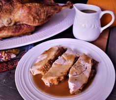 two white plates topped with meat and gravy next to a cup of coffee