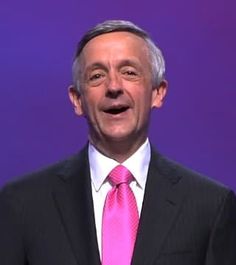 a man in a suit and pink tie is making a funny face at the camera