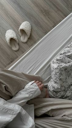 a person laying in bed with slippers on the floor