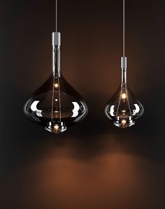 two lights are hanging from the ceiling in a dark room, one is turned on