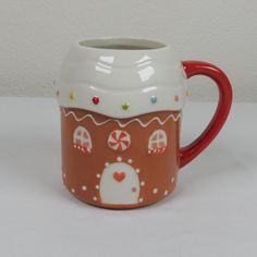 a ceramic mug with gingerbread house and candy canes on the inside is sitting on a white surface