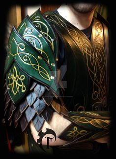 a close up of a person wearing a green and gold armor with intricate designs on it