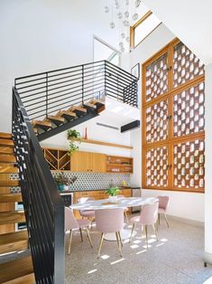 a dining room table with pink chairs under a stair case next to a wooden door