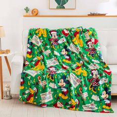 a green mickey mouse christmas blanket sitting on top of a couch