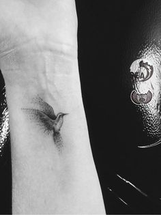 a small bird tattoo on the wrist is shown next to a black and white photo