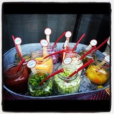 jars filled with pickles and vegetables sitting on top of an ice tray in front of a window