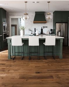 a kitchen with green cabinets and white chairs