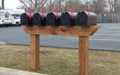 several mailboxes are lined up on a wooden post in front of a parking lot