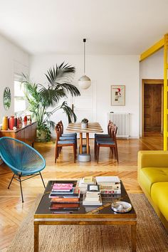 a living room filled with furniture next to a table and books on top of a hard wood floor