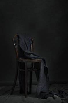 a chair with a blanket on top of it in front of a dark wall and floor