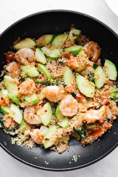 shrimp, zucchini and couscous in a skillet on a white surface