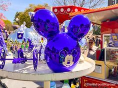 purple mickey mouse head ornaments on display at an amusement park