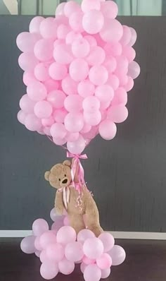 a teddy bear sitting on top of a bunch of balloons