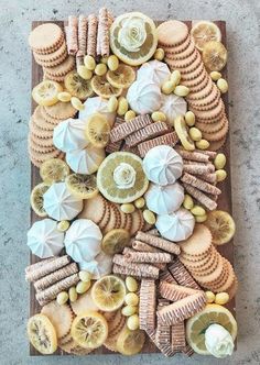 a wooden board topped with lots of different types of cookies and lemons on top of it