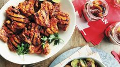 chicken wings and vegetables on a plate next to two glasses of water, napkins and spoons