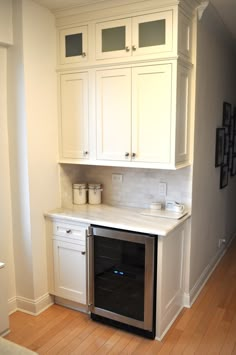 a kitchen with white cabinets and an oven in the center, along with hardwood flooring