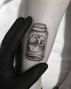 a black and white photo of a jar with a cat in it on the arm