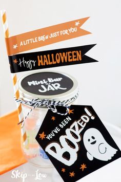 there is a halloween treat in a jar on the table with tags attached to it