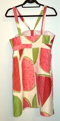 a dress hanging on a hanger in front of a white wall with a red and green pattern