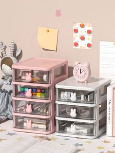 an assortment of toys and books on a table with pink wallpaper in the background