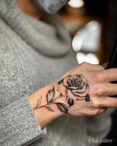 a woman with a rose tattoo on her wrist holding a cell phone in her hand