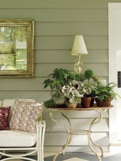 a table with potted plants sitting on top of it next to a white chair