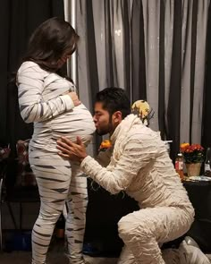 a man and woman dressed up as zebras in front of a curtained room