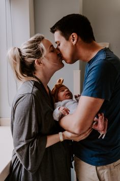 a man and woman kissing while holding a baby