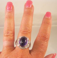 "Gorgeous STS Chuck Clemency big genuine cabochon amethyst and sterling silver ring. Ring size 12. Measures 20.5mm in the center front. The amethyst stone measures approximately 16mm x 12mm. There are 10 - 2mm each of the clear stones. Total weight is 12.3 grams. Marked 925 STS. In excellent gently used vintage condition. Please note, items in photos may appear larger than actual size. Be sure to read description for size and check all photos for comparison. 187.5006 ---------------------------- Purple Band, Vintage Ring, Amethyst Stone, Ring Vintage, Beautiful Gift Boxes, Ring Ring, Sterling Silver Ring, Vintage Rings, Beautiful Rings