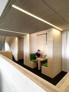 a man is sitting at a desk in an office with green chairs and white walls