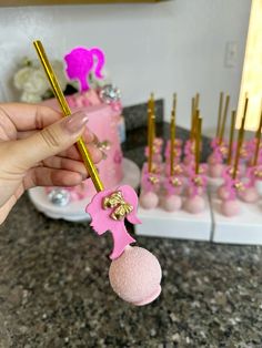 a person holding a pink pom - pom in front of a cake