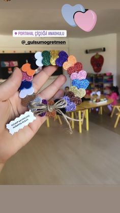 someone is holding out their colorful bracelets in the middle of a room filled with tables and chairs