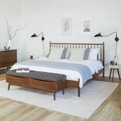 a bedroom with white walls and wood floors has a bed, nightstands, and two lamps