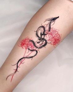 a woman's leg with a dragon and flowers tattoo on the side of her arm