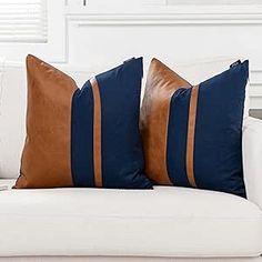 two brown and blue pillows sitting on top of a white couch