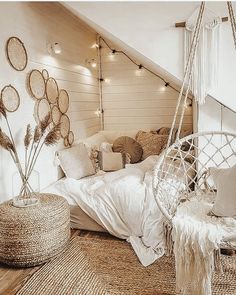 a bedroom with white bedding and hanging decorations on the wall, including a hammock chair