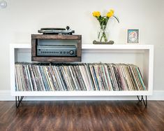 a record player sitting on top of a white shelf next to a bunch of records