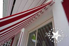 a red and white striped awning hanging from the side of a house next to a window