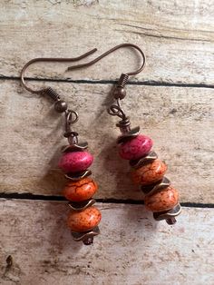 Earrings are on a copper wire with copper spacers, in between a peachy orange color bead. Handmade Adjustable Rust Earrings, Bohemian Orange Copper Earrings, Orange Copper Bohemian Earrings, Handmade Copper Round Bead Earrings, Unique Copper Earrings With Dangling Beads, Red Copper Earrings, Handmade Orange Copper Earrings, Orange Copper Dangle Earrings, Orange Copper Earrings For Gift