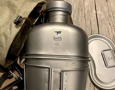 a stainless steel ketchup bottle sitting on top of a wooden table next to a bag